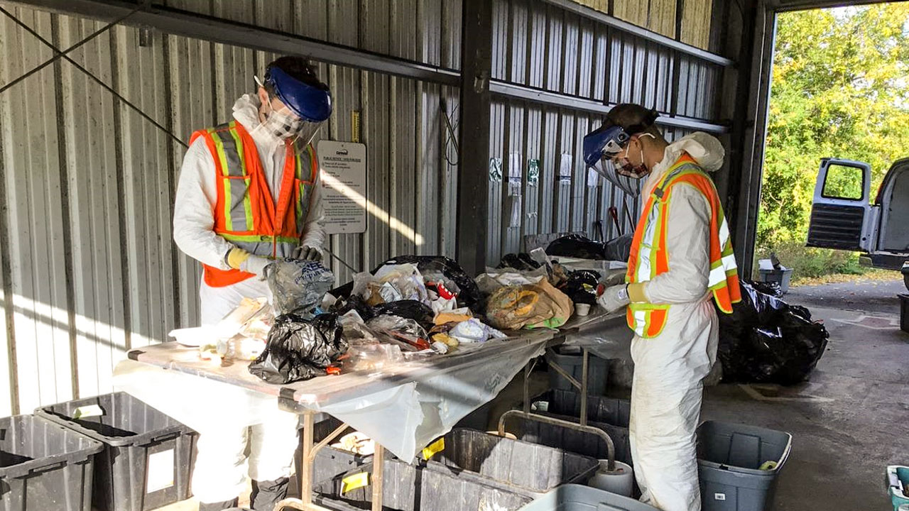 Deux travailleurs portant un EPI évaluent la quantité de matières organiques dans le flux de déchets