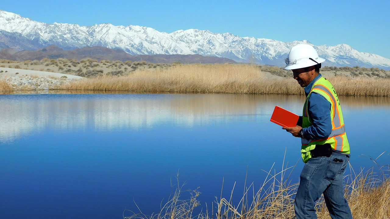 Un technicien de Tetra Tech se tient devant un plan d’eau à Owens Lake, en Californie