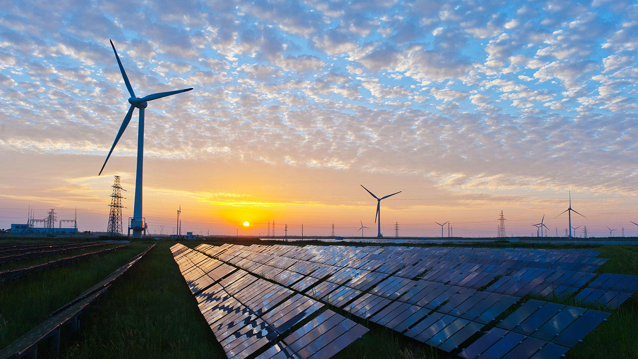 Des panneaux solaires et des éoliennes photographiés au coucher du soleil représentent l’ingénierie en matière d’énergie renouvelable de Tetra Tech