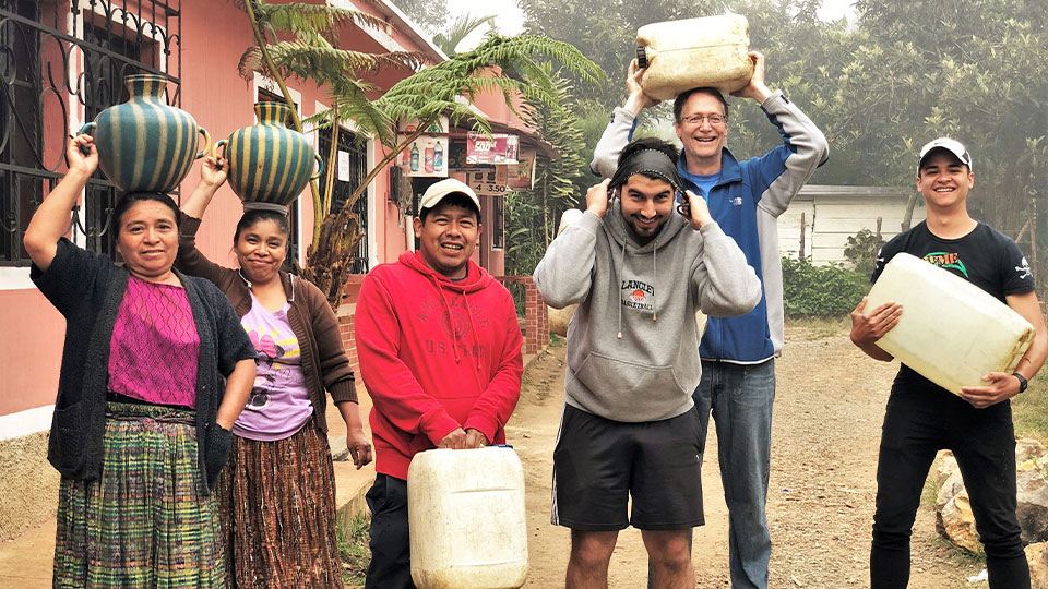 Un groupe de personnes aide des villageois Maya au Guatemala à porter des cruches d’eau jusqu’à leur domicile
