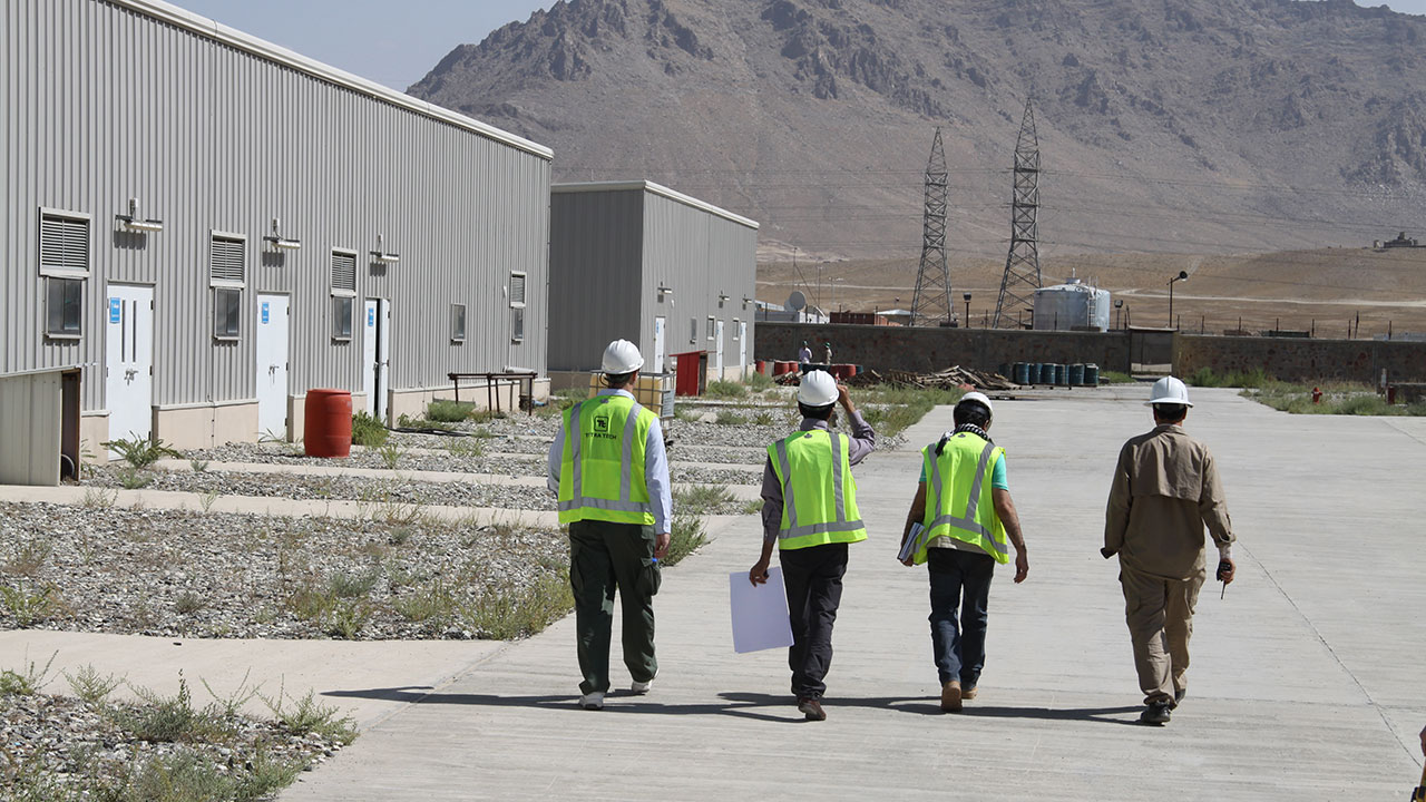Quatre employés de Tetra Tech marchent ensemble sur le site d’un projet d’ingénierie électrique