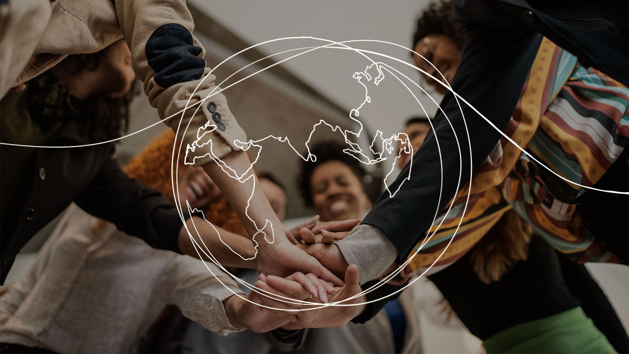 Tracé d’une ligne représentant un globe terrestre superposé sur une photo montrant un groupe diversifié de personnes empilant leurs mains au centre du groupe