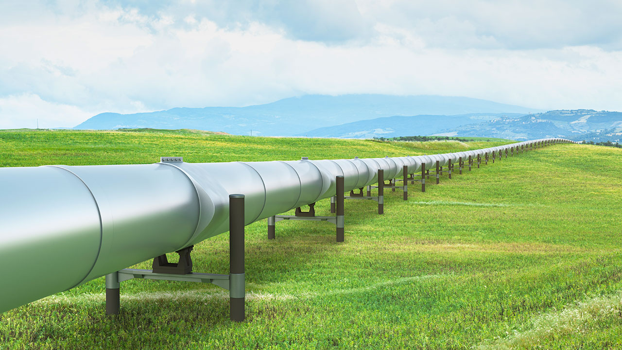 Un pipeline hors-sol couleur argent traverse une grande étendue verte