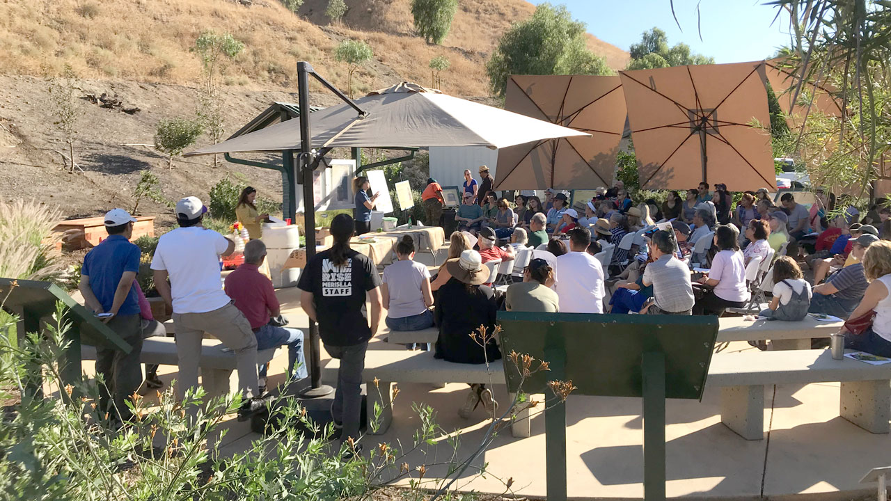 Groupe de personnes réuni en plein air pour entendre parler des moyens de réduire les déchets alimentaires