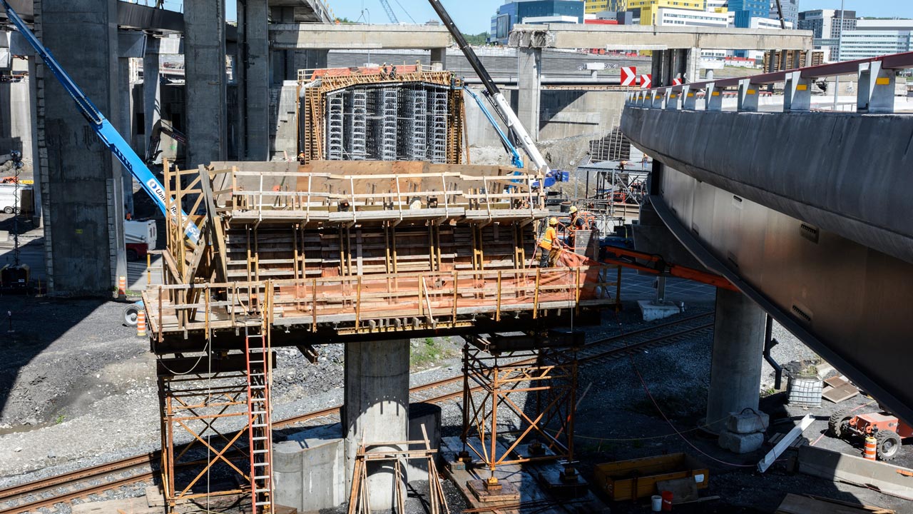 Chantier de construction d’un tunnel et de ponts, à proximité d’anciennes structures en cours de démolition