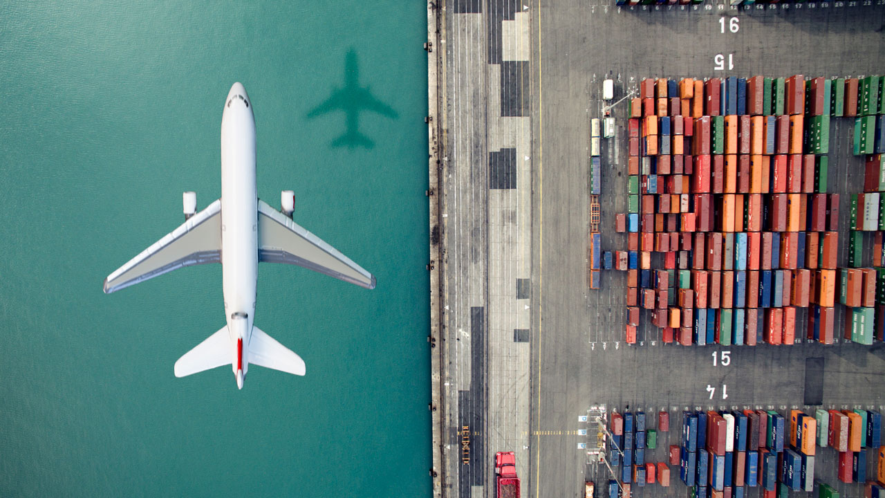 Vue aérienne d’un avion survolant des conteneurs de marchandises dans un port