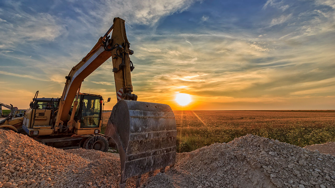 Une excavatrice sur un site de construction au coucher du soleil