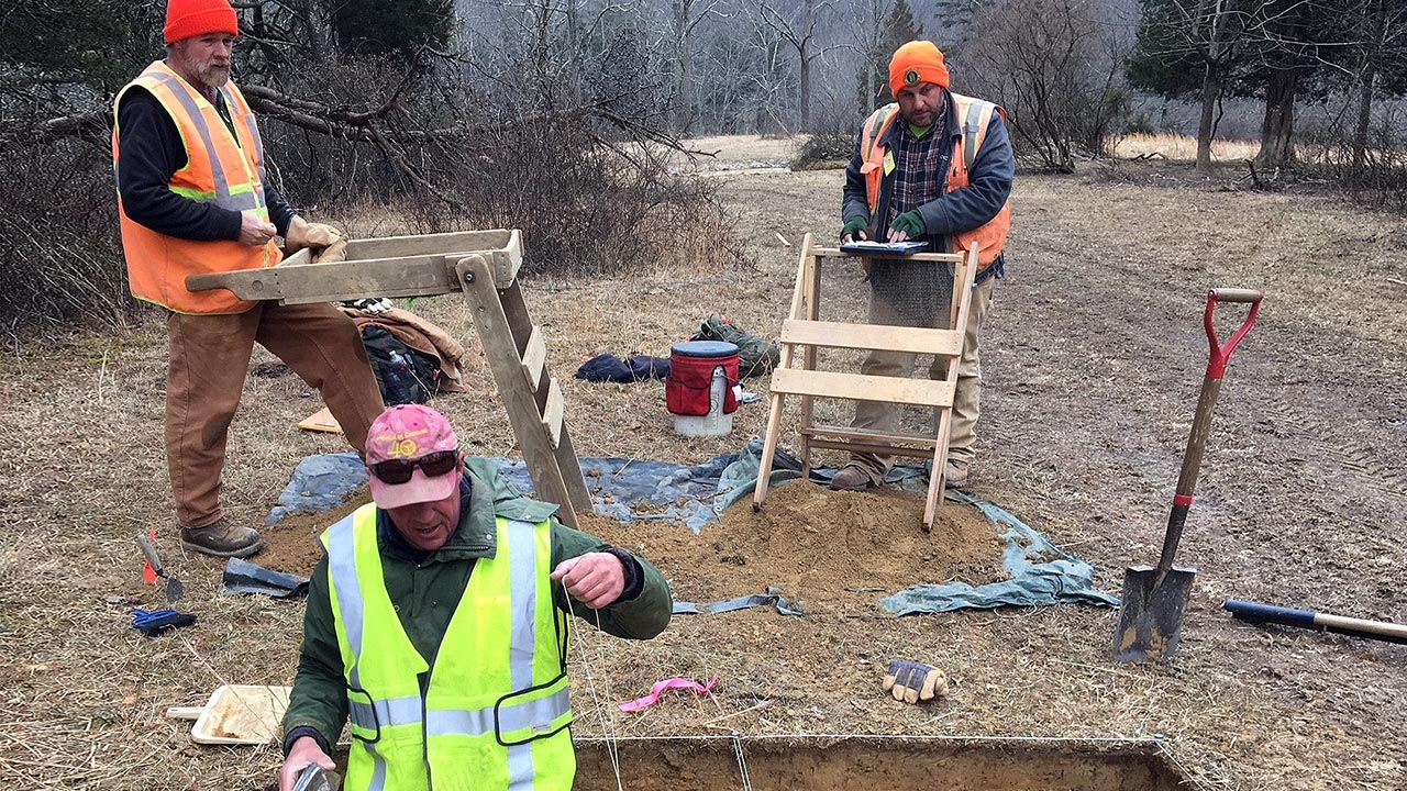 Trois techniciens portant des gilets de sécurité procèdent à des études de ressources culturelles en Virginie occidentale