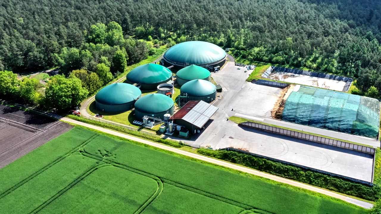 Installation de digestion anaérobie pour la transformation de déchets organiques en produits bénéfiques, avec des arbres et des champs environnants