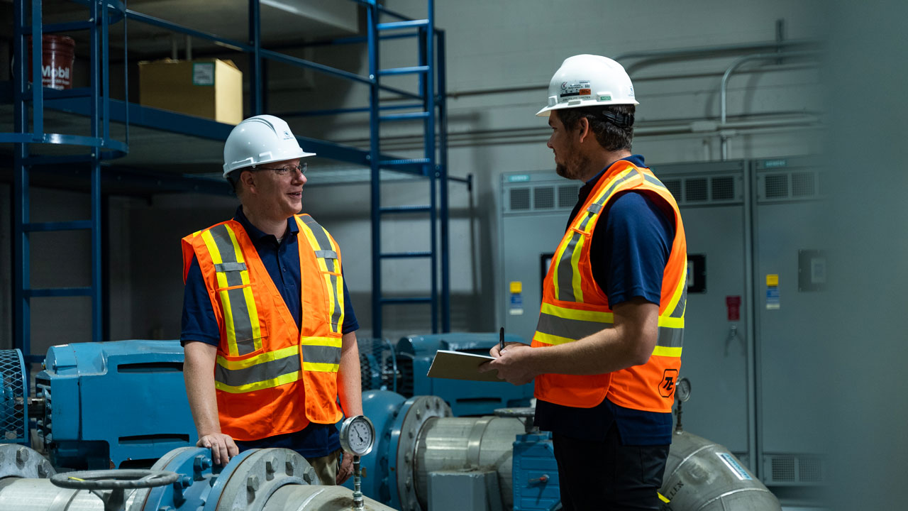 Deux ingénieurs masculins qui se trouvent dans une usine de traitement des eaux intérieures, en train de discuter